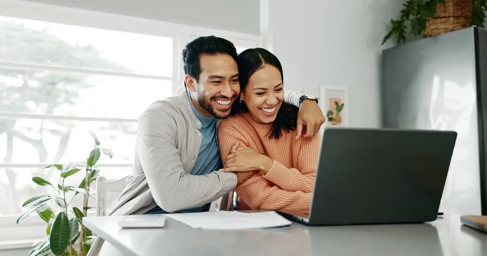 A smiling couple at a laptop computer