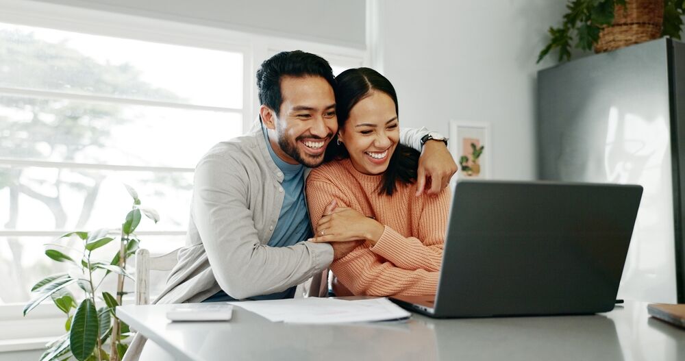 A smiling couple at a laptop computer